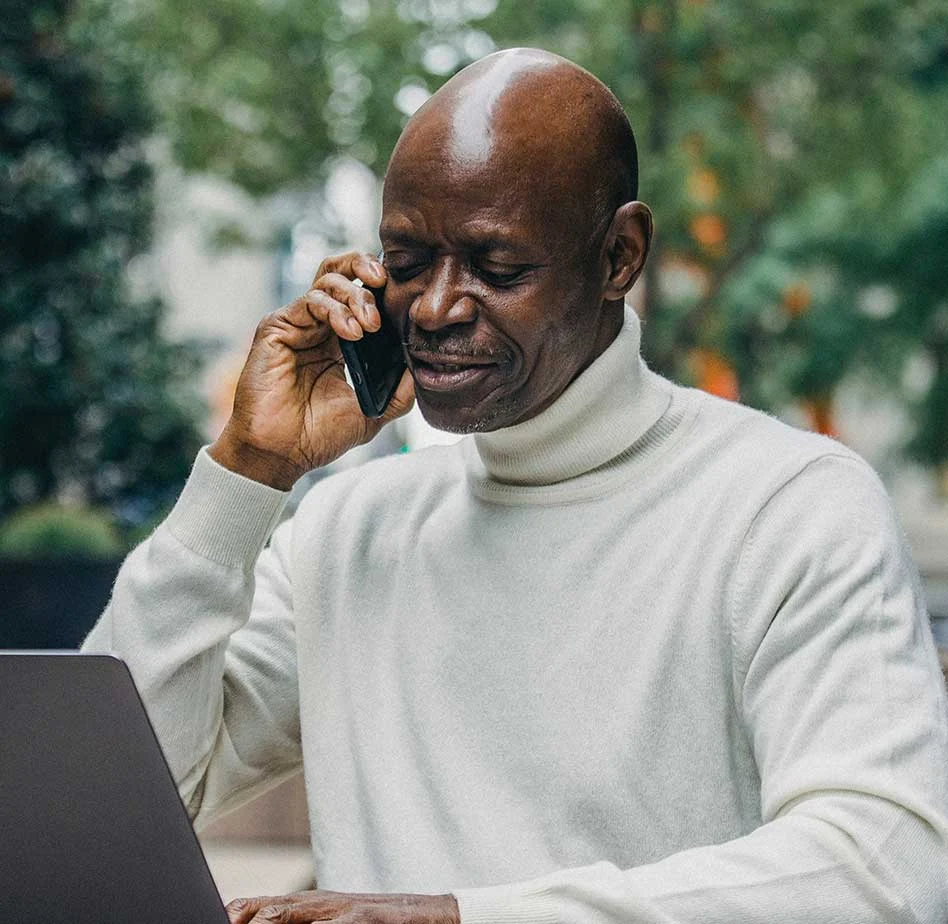 ac-testimonial-4 Client testimonial photo of a man using a laptop and phone outdoors